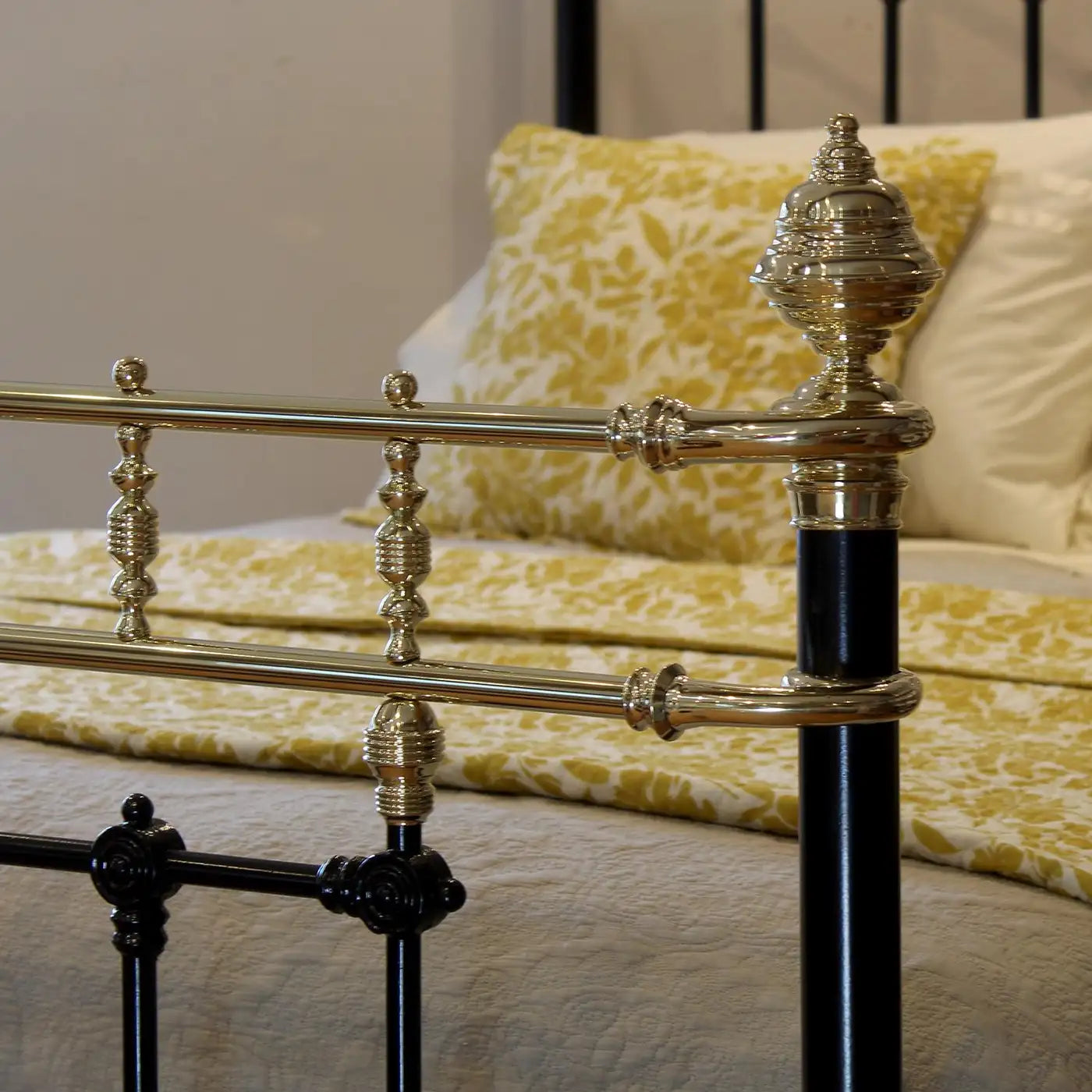 Close-up of a decorative bed with gold and black metal frame and yellow bedding.