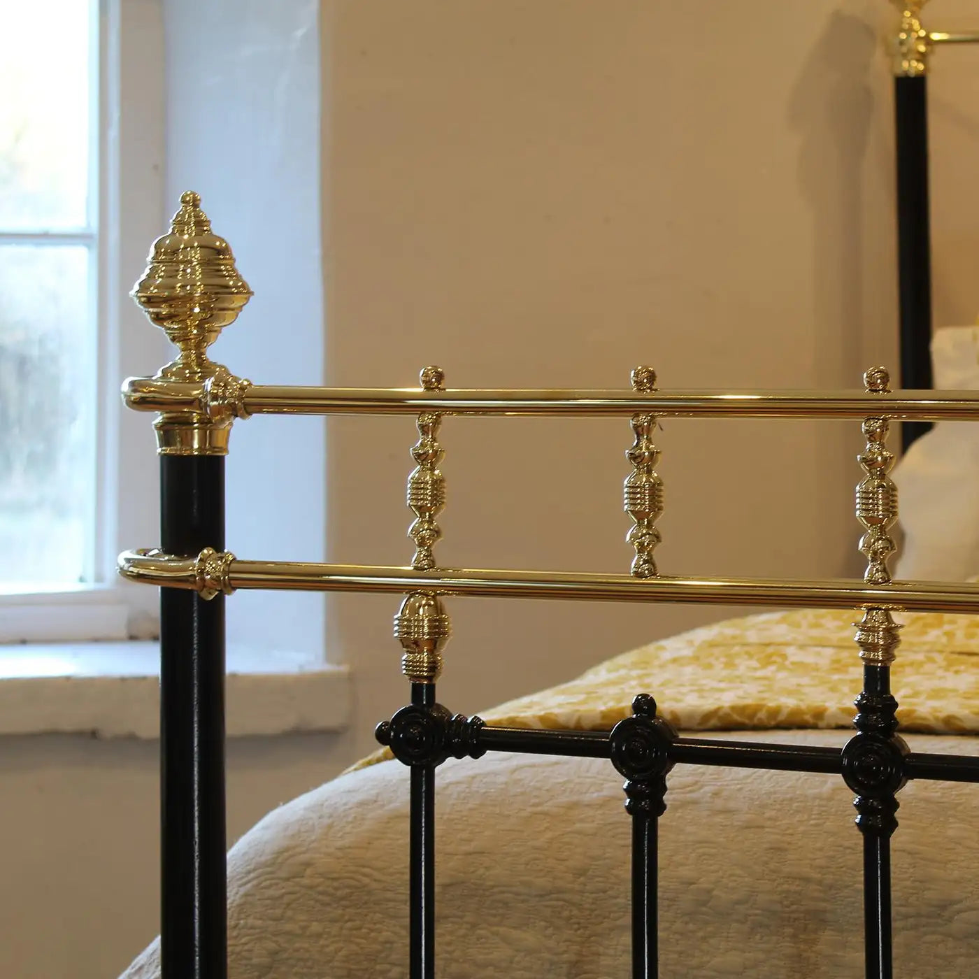 Close-up of a decorative metal bed frame with gold accents in a bedroom setting.