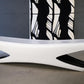 Modern white bench with a black and white patterned rug in the background