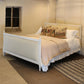 Bedroom with a white bed and decorative pillows on a striped rug.