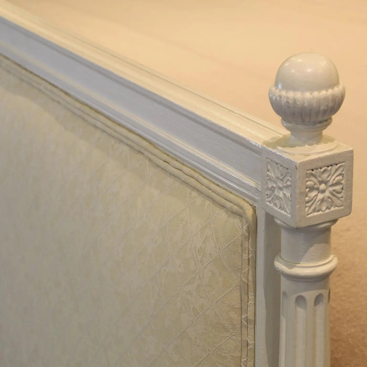 Decorative headboard with intricate carvings on a beige wall