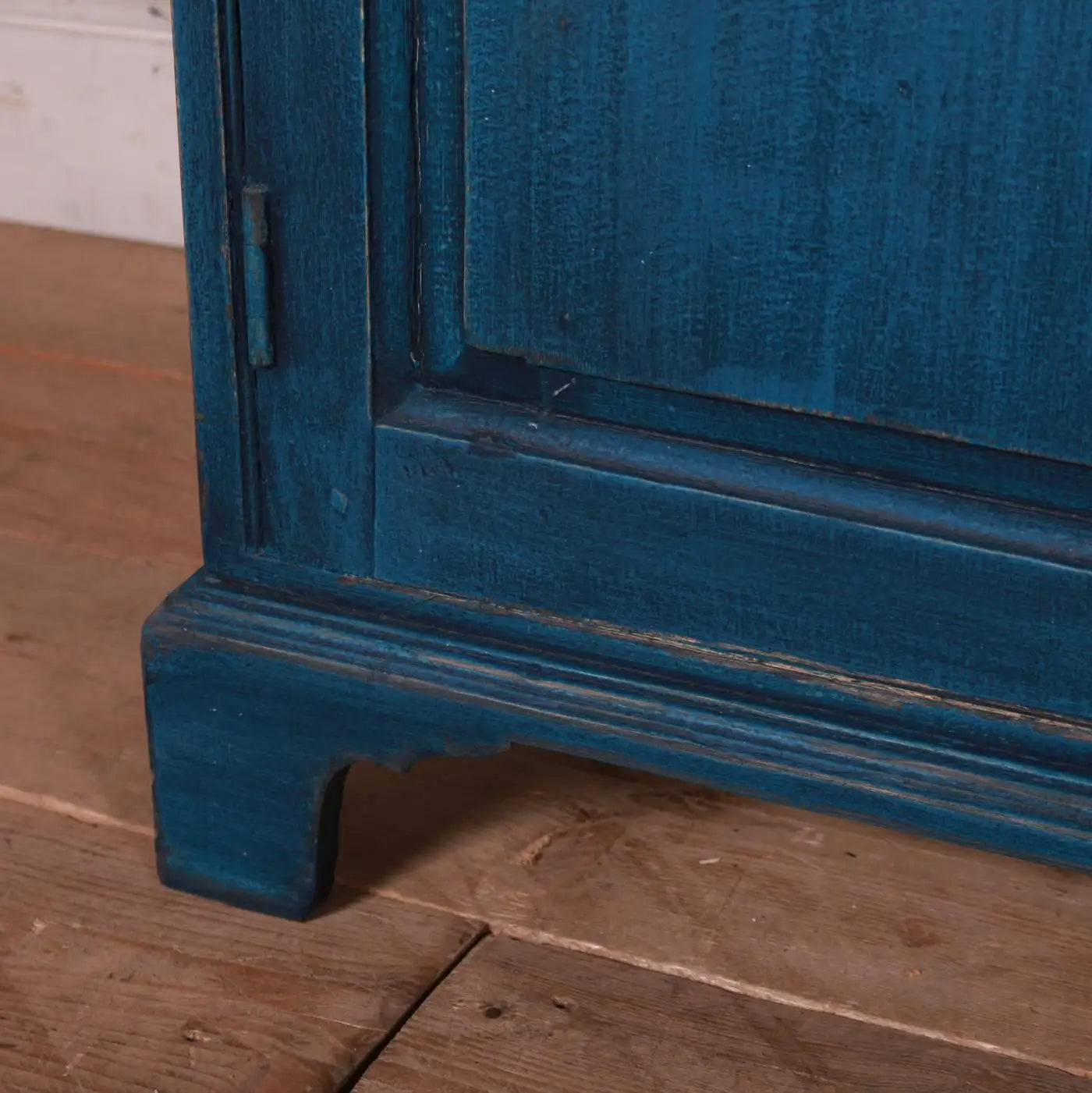 Close-up of a blue wooden cabinet corner on a wooden floor