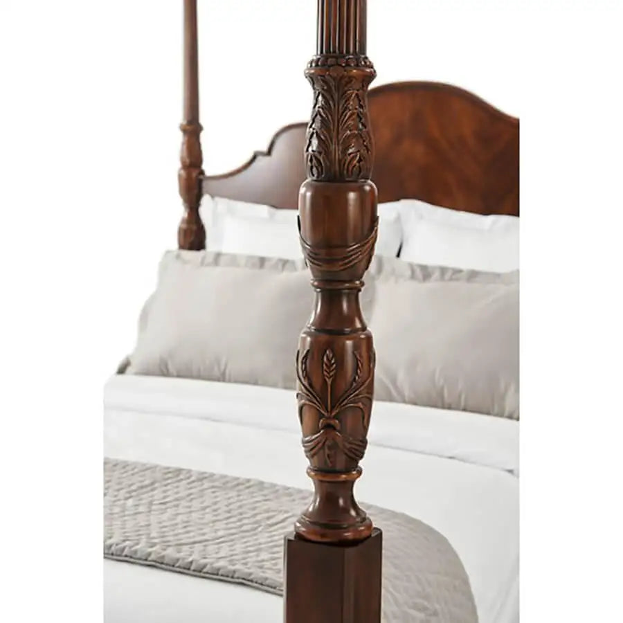 Wooden bed post with intricate carvings on a bed with white bedding.