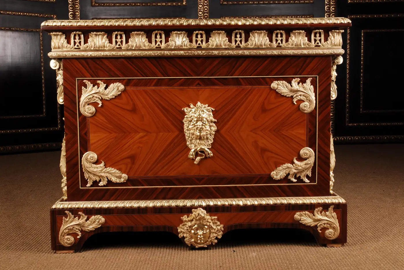 Decorative wooden chest with intricate carvings and gold accents on a brown surface.