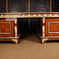 Wooden desk with intricate carvings and gold accents against a dark wall.