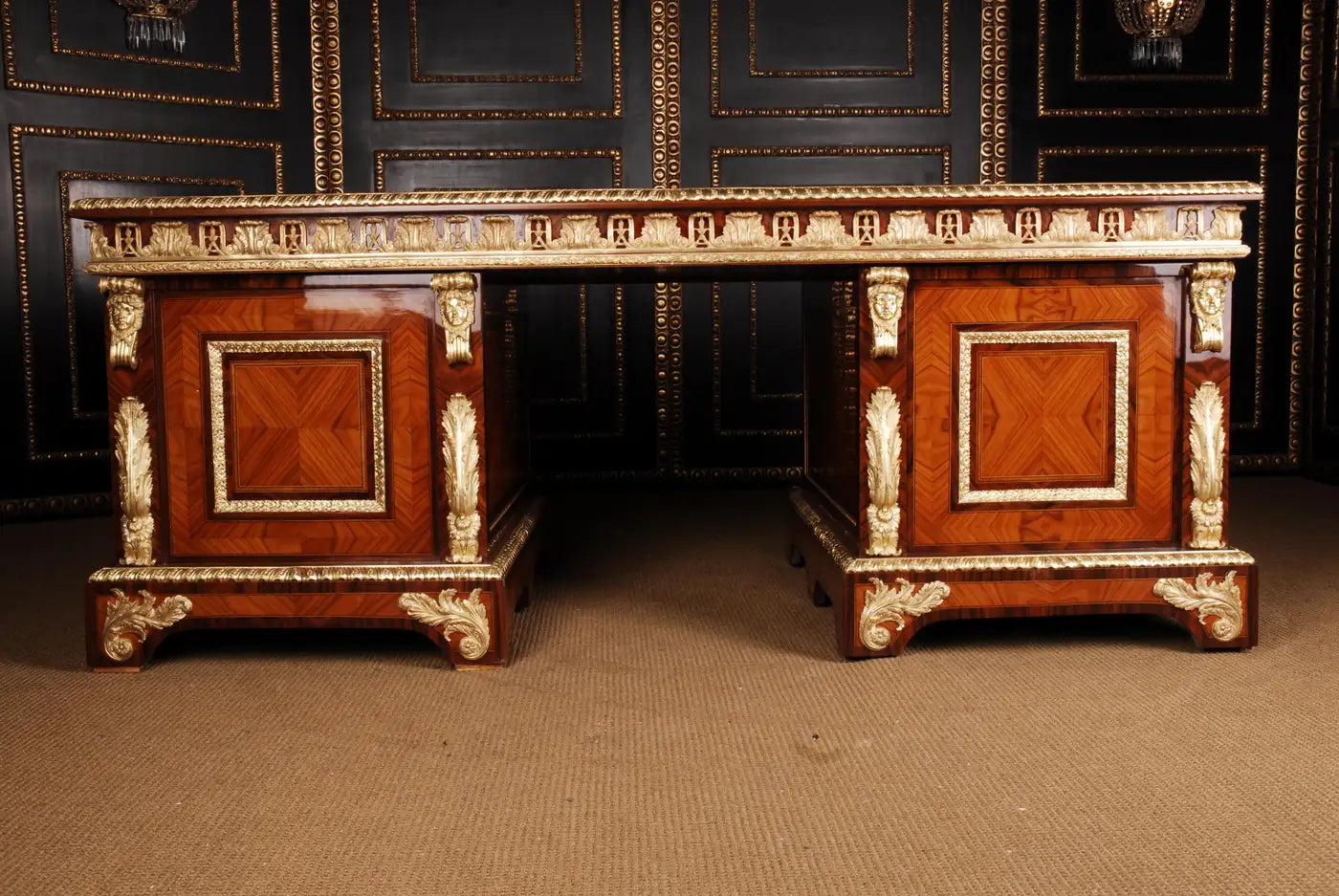 Wooden desk with intricate carvings and gold accents against a dark wall.