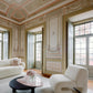 Luxurious living room with ornate ceiling and walls, featuring a white sofa and chair.