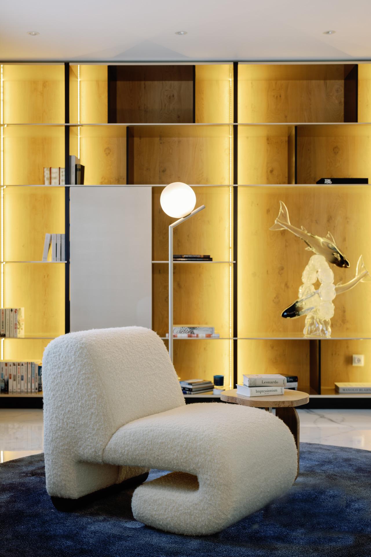 Modern white chair in a room with gold wall panels and decorative elements.