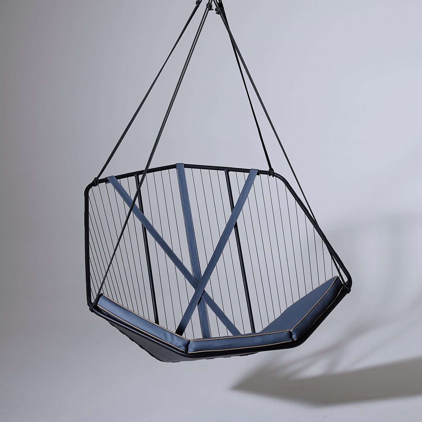 Hanging chair with geometric design on a plain background