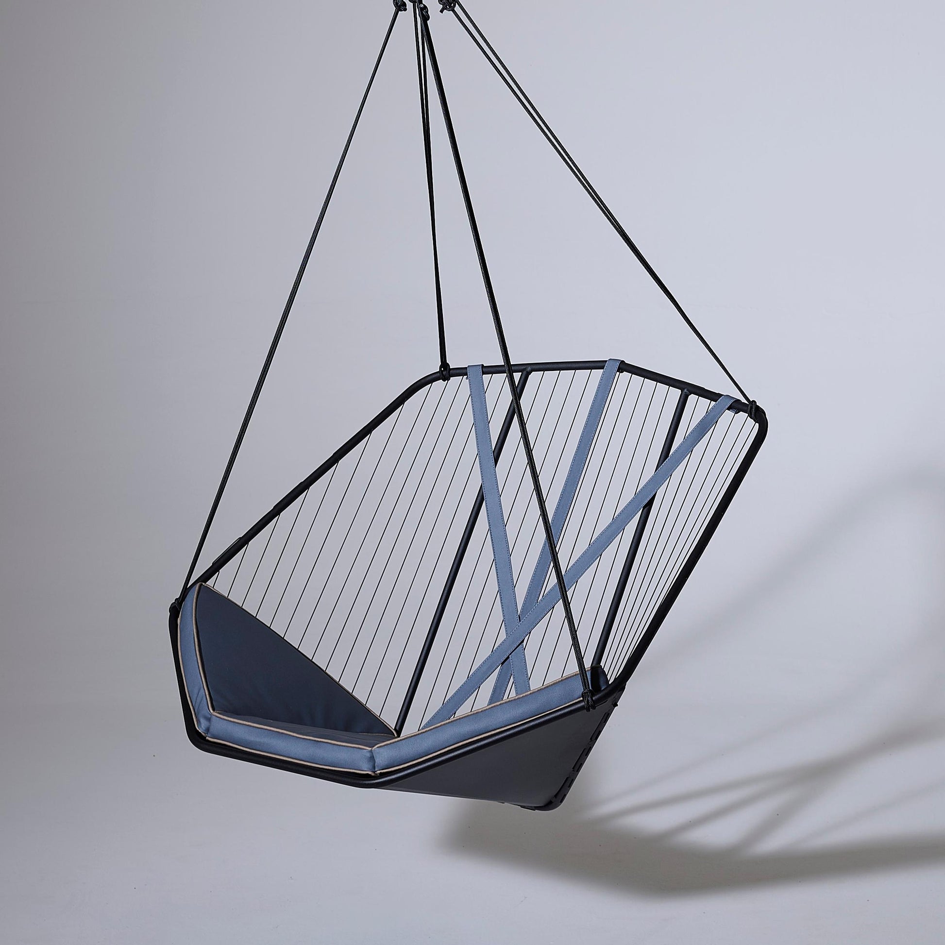 Hanging chair with geometric design on a plain background