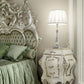 Decorative bedroom with ornate headboard and nightstand with lamp.