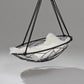 Hanging chair with white cushion and black metal frame on a gray background
