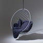Modern hanging chair with a dark blue knitted blanket on a gray background