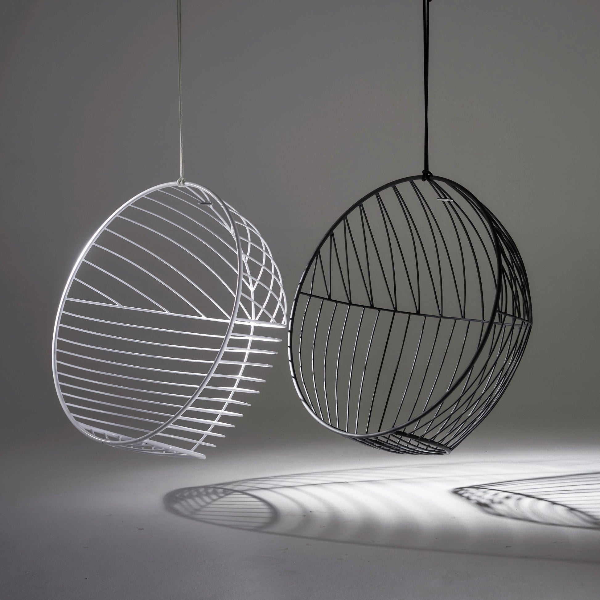 Two wireframe spherical chairs, one white and one black, on a gray background.