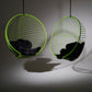 Two green wireframe hanging chairs with black cushions on a gray background