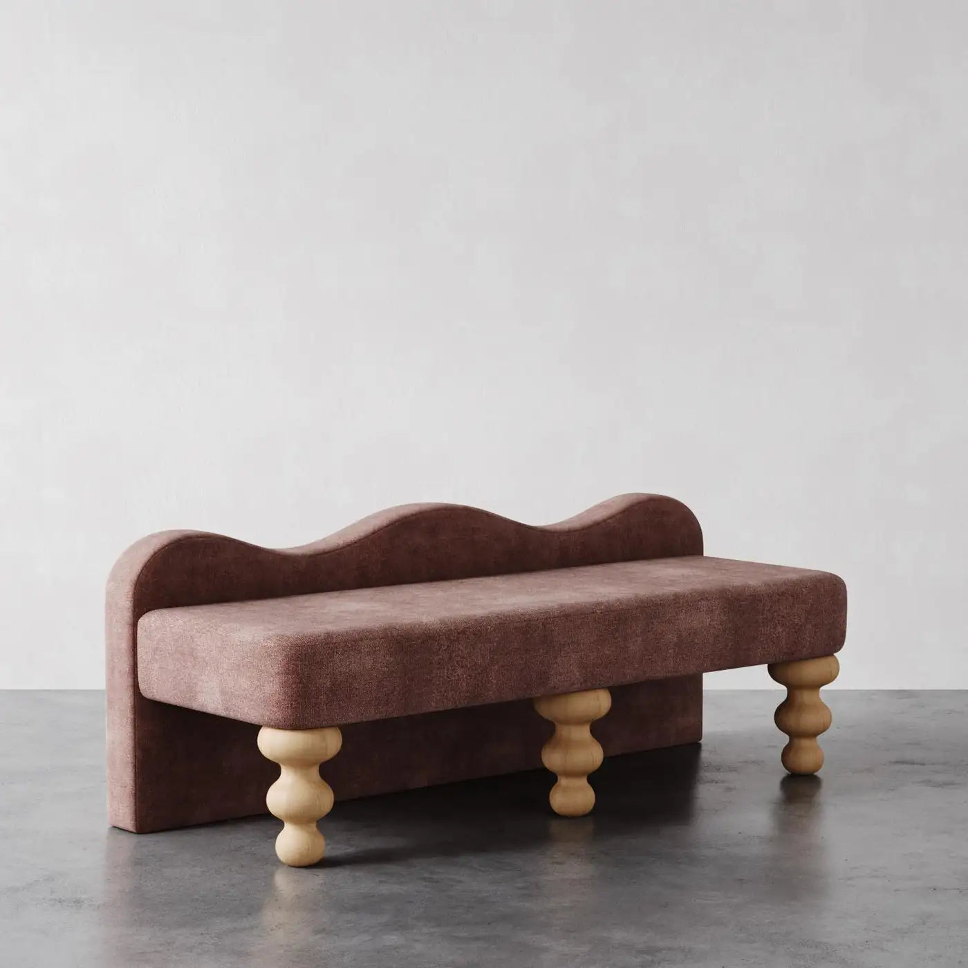 Brown upholstered bench with wooden legs on a gray floor against a white wall