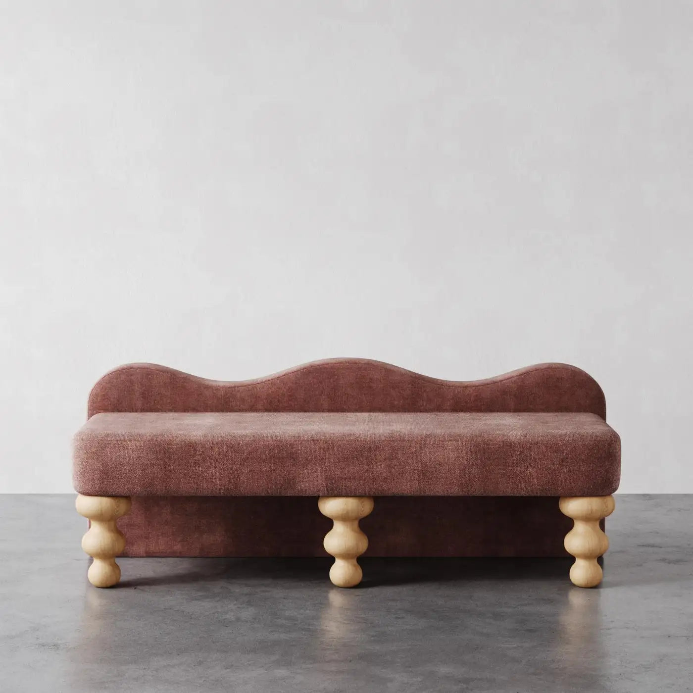 Pink velvet bench with wooden legs on a gray floor and light gray background