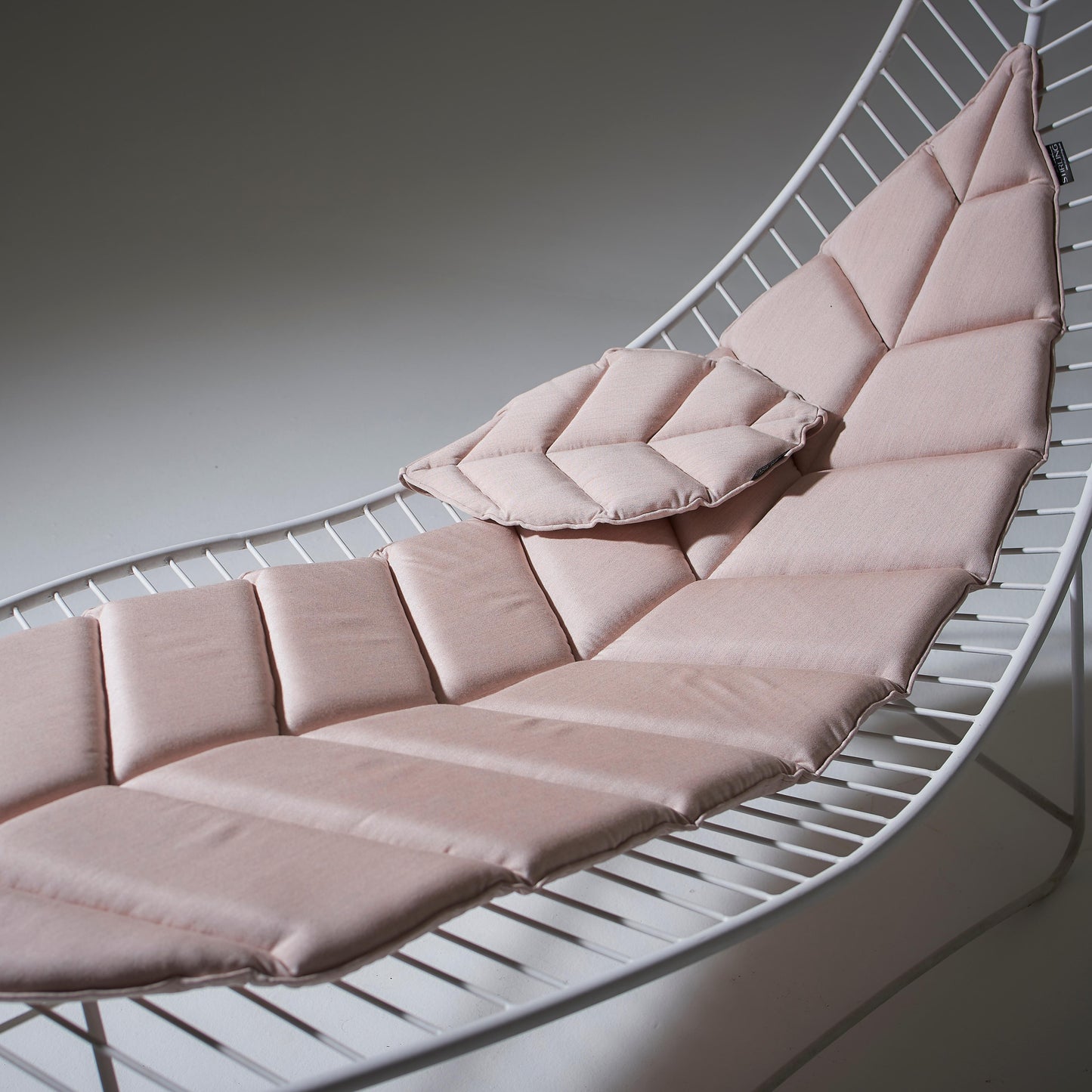 Pink cushioned lounge chair on a white background