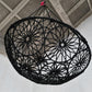 Black woven chair hanging from a ceiling