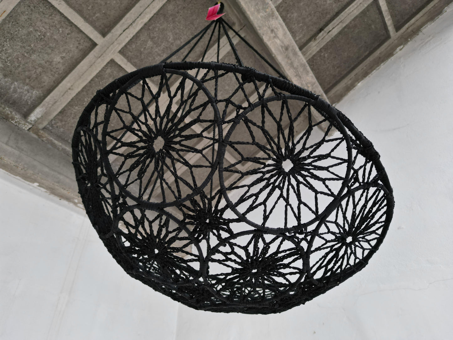 Black woven chair hanging from a ceiling