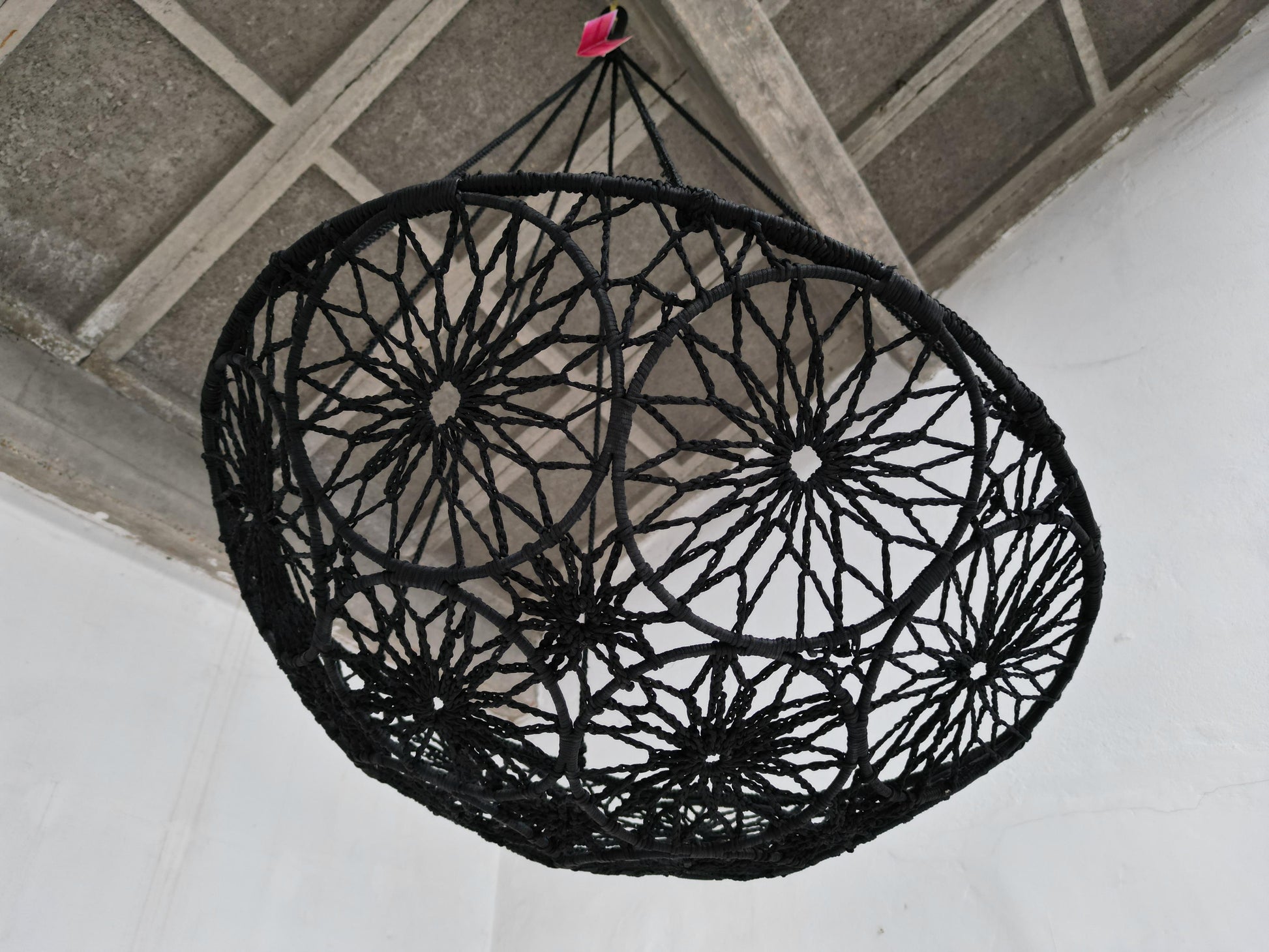Black woven chair hanging from a ceiling