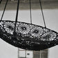 Black woven swing hanging against a white wall.