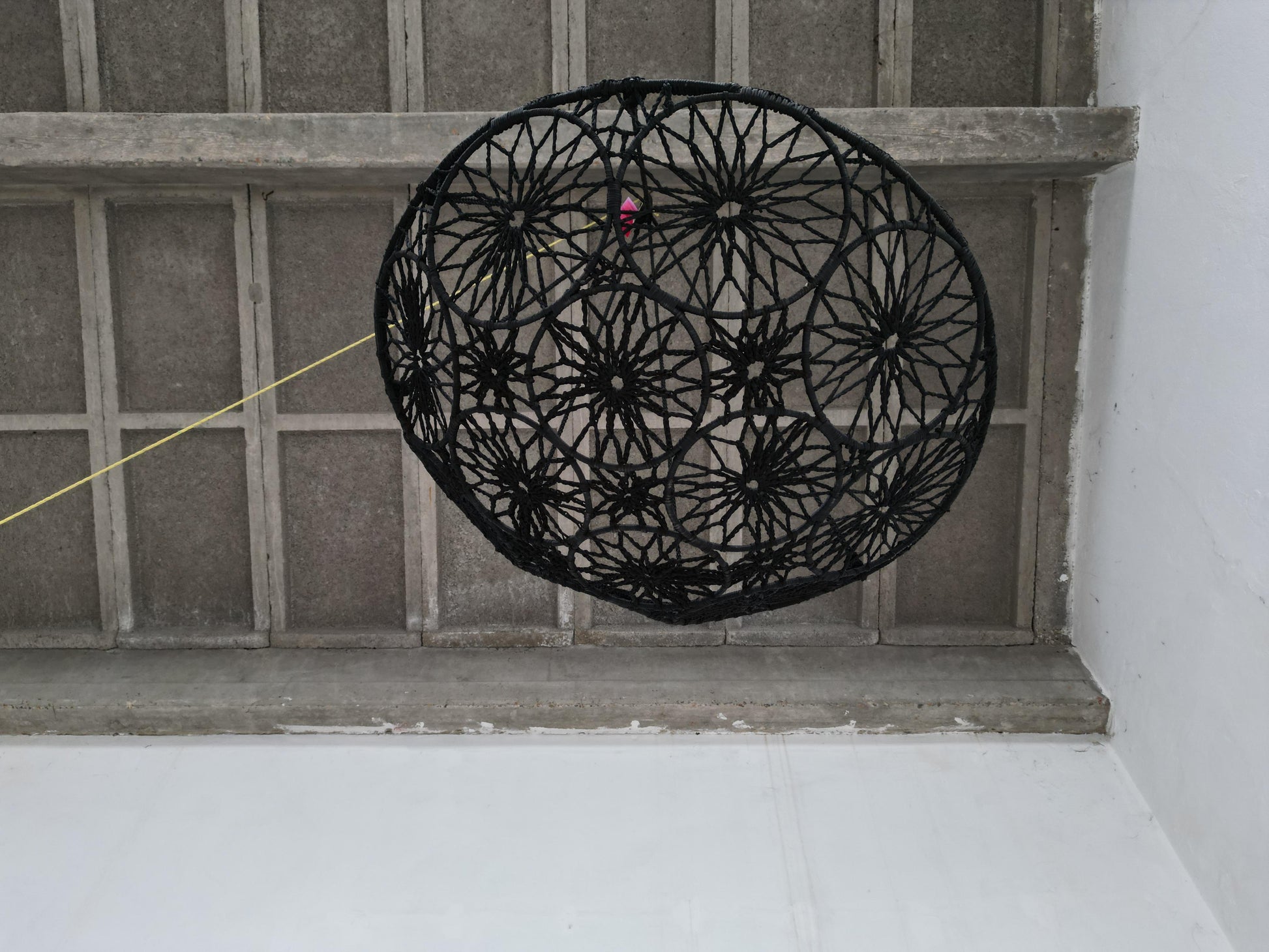 Black woven basket on a concrete step with a textured wall background