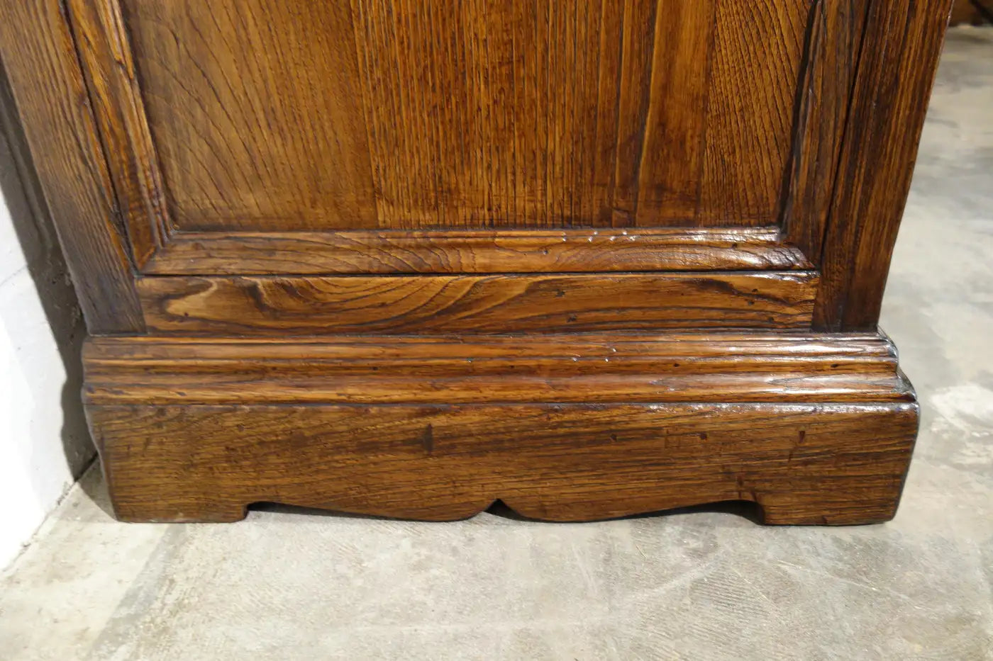 Close-up of a wooden cabinet corner with a marble floor.