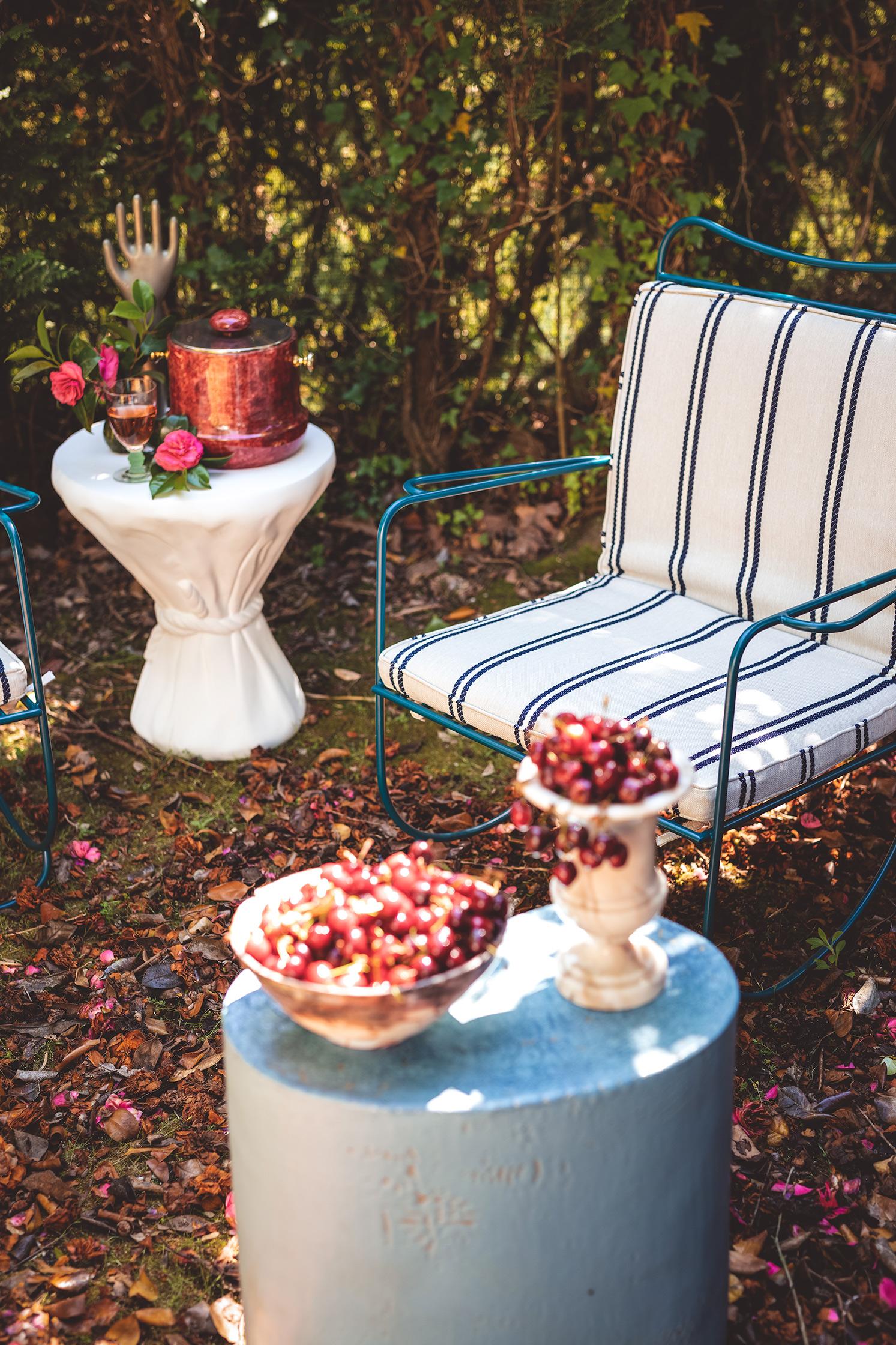 Outdoor setting with a chair, small table, and decorative items in a garden.