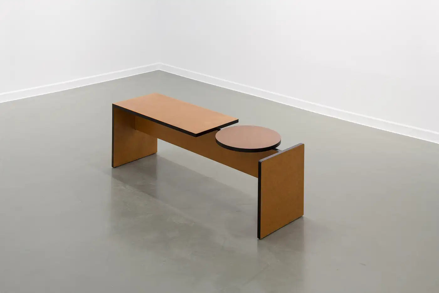 Minimalist wooden bench with round seat in a plain room