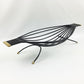 Black wire bird sculpture with gold accents on a white background