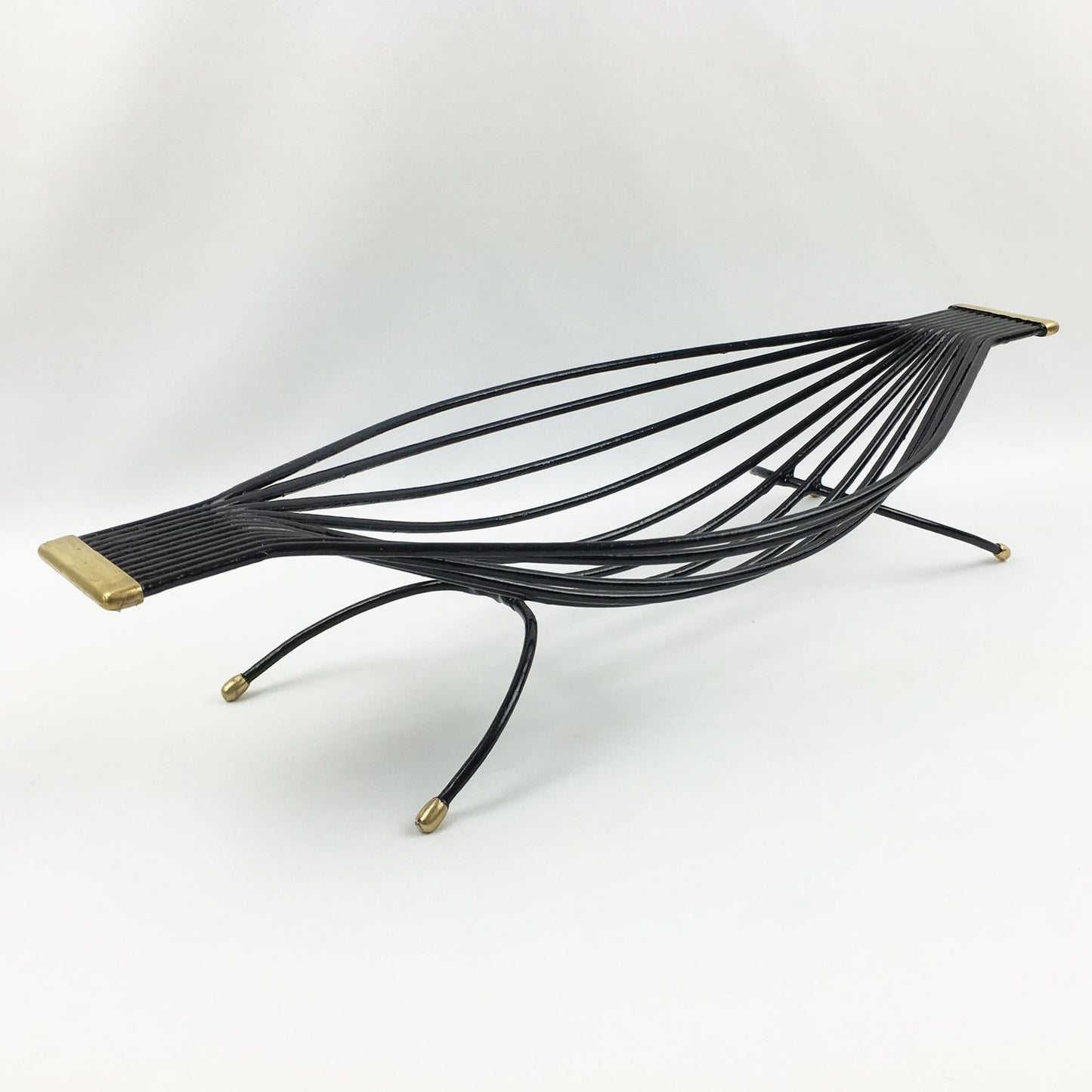Black wire bird sculpture with gold accents on a white background