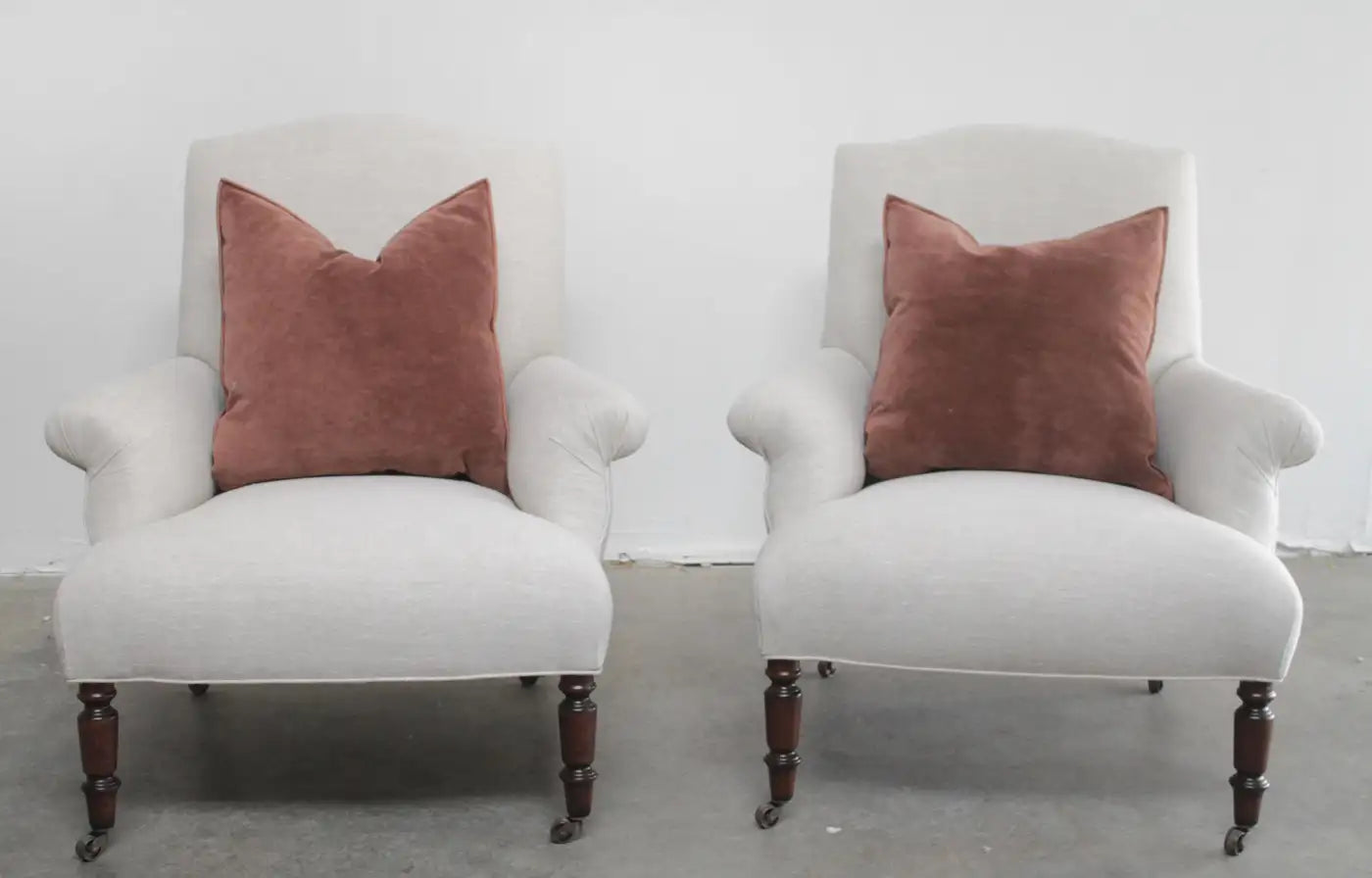 Two white armchairs with brown cushions on a plain background
