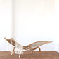 Woven chair with fringe on a wooden floor against a white wall