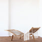 Wooden lounge chair with a white woven backrest in a minimalistic room.