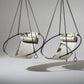 Two metallic hanging chairs with black straps on a gray background