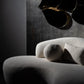 Modern chair with textured surface against a dark wall with a decorative light fixture.