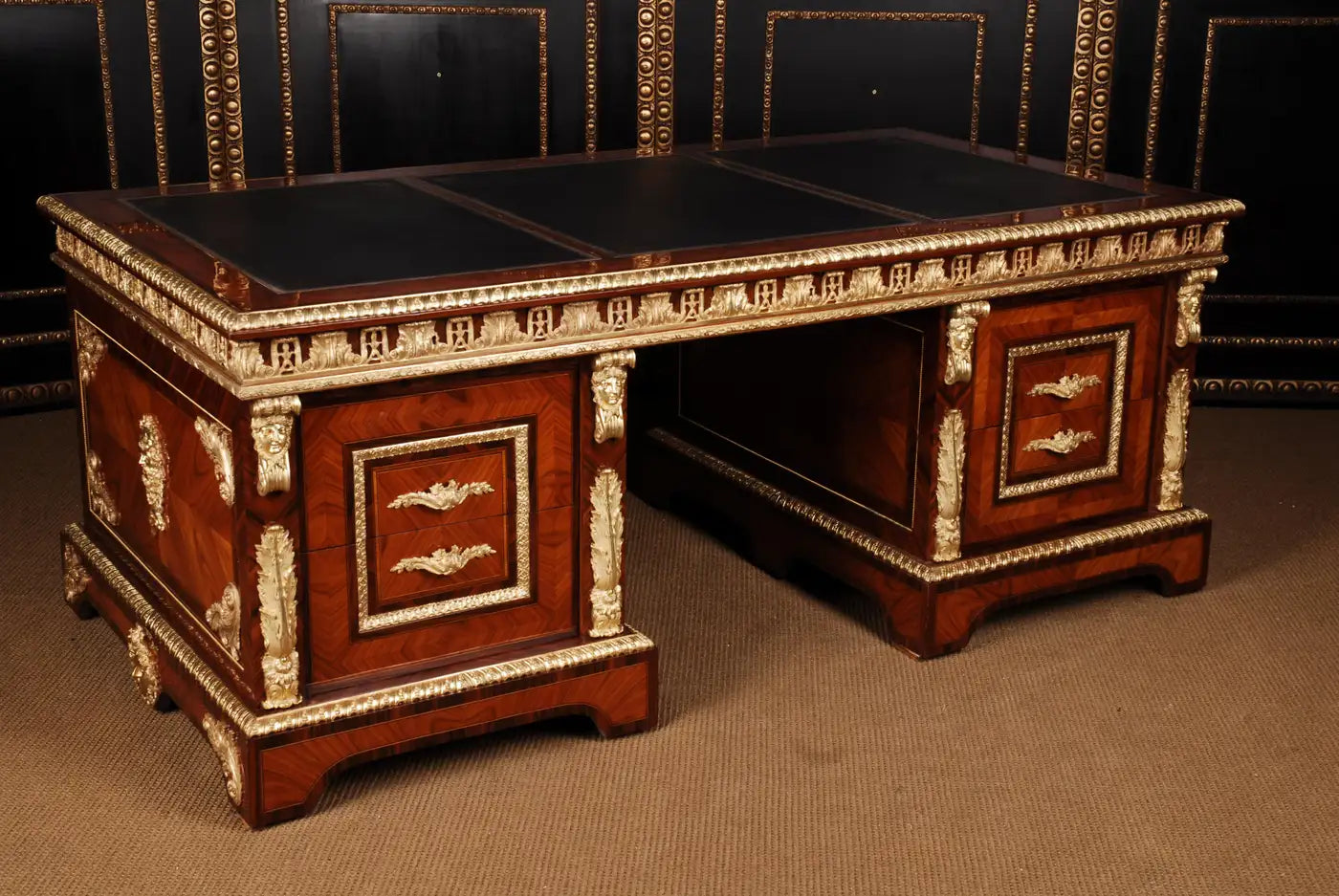 Decorative wooden desk with intricate carvings and leather surfaces.