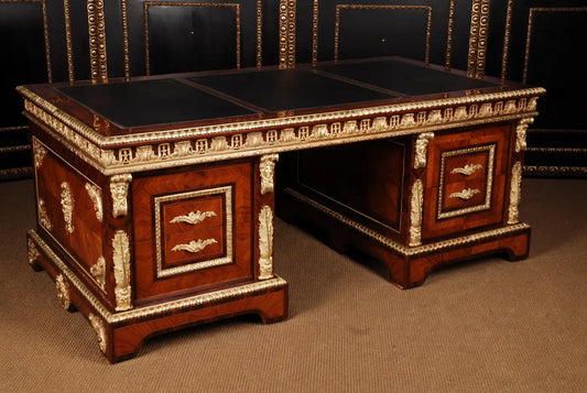 Decorative wooden desk with intricate carvings and leather surfaces.
