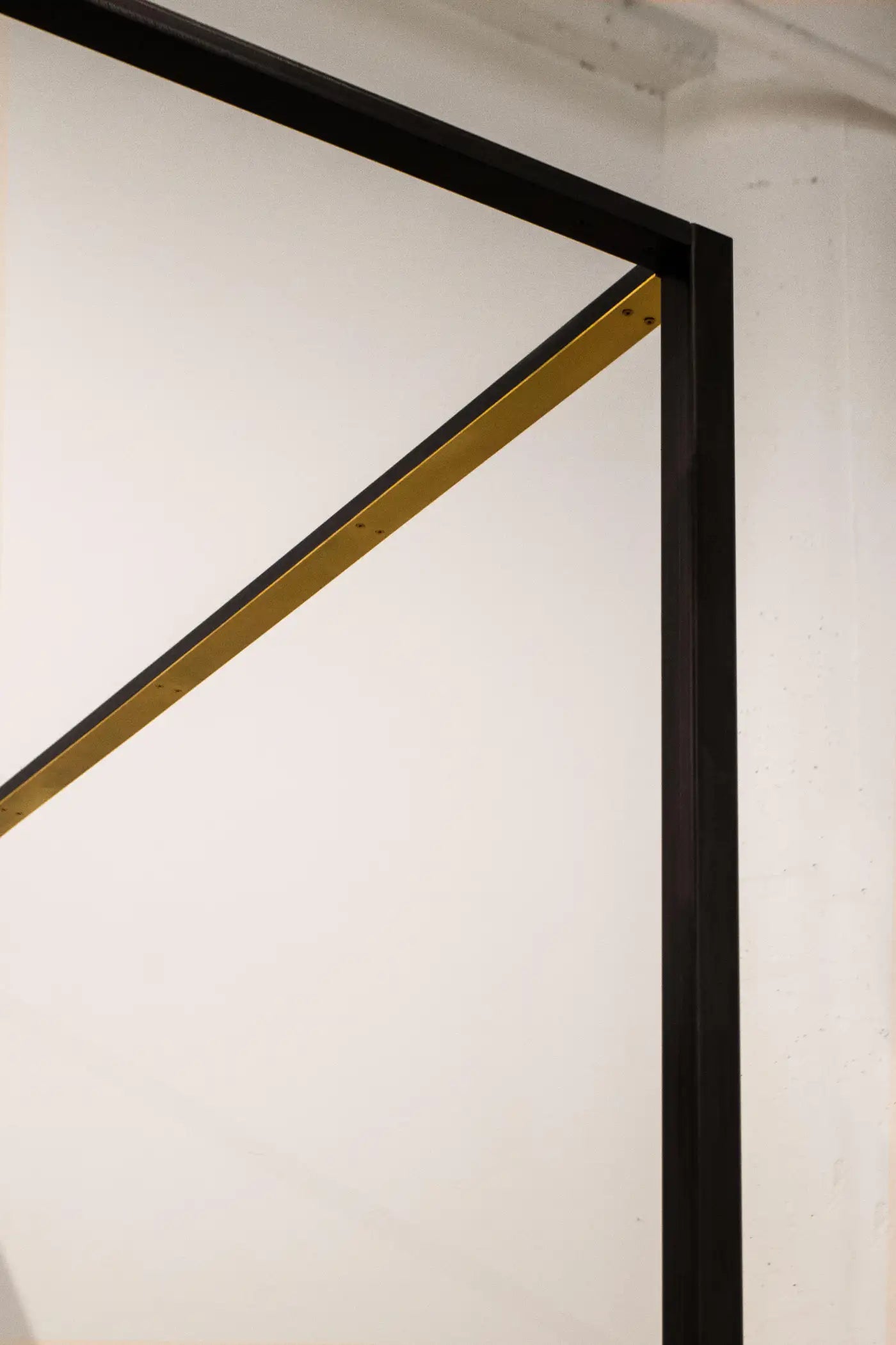 Close-up of a black and gold geometric art piece on a white wall.