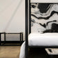 Modern bedroom with a black four-poster bed and abstract art on the wall.