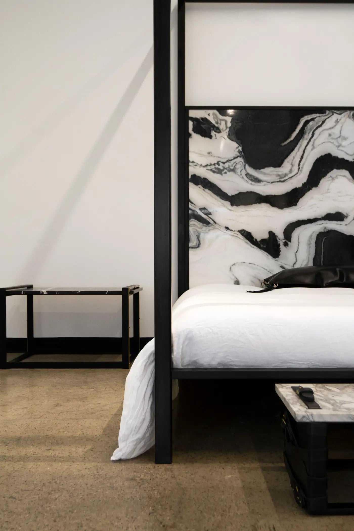 Modern bedroom with a black four-poster bed and abstract art on the wall.