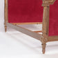 Decorative bed with gold frame and red velvet backrest on a white background