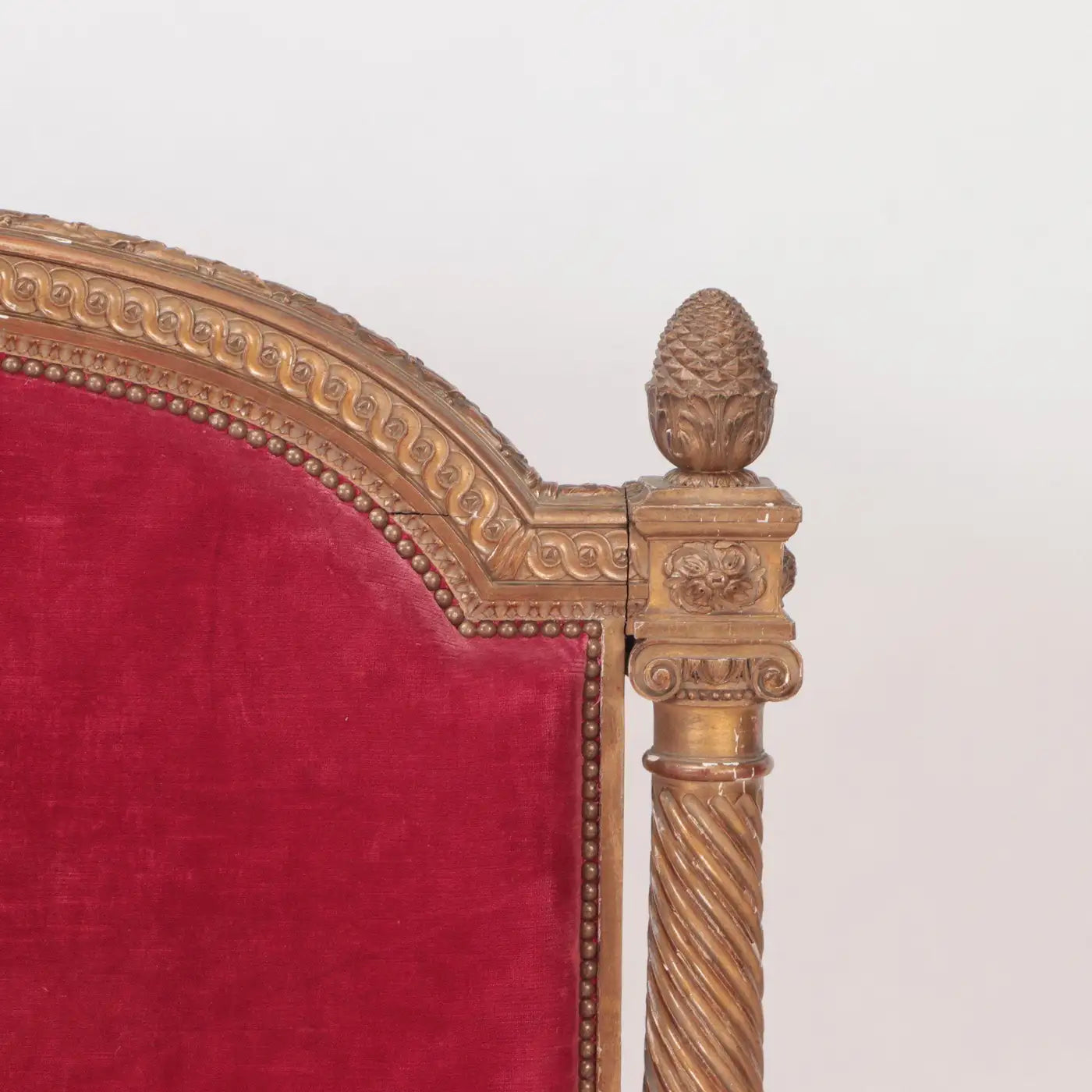Close-up of a chair with gold frame and red velvet seat on a white background