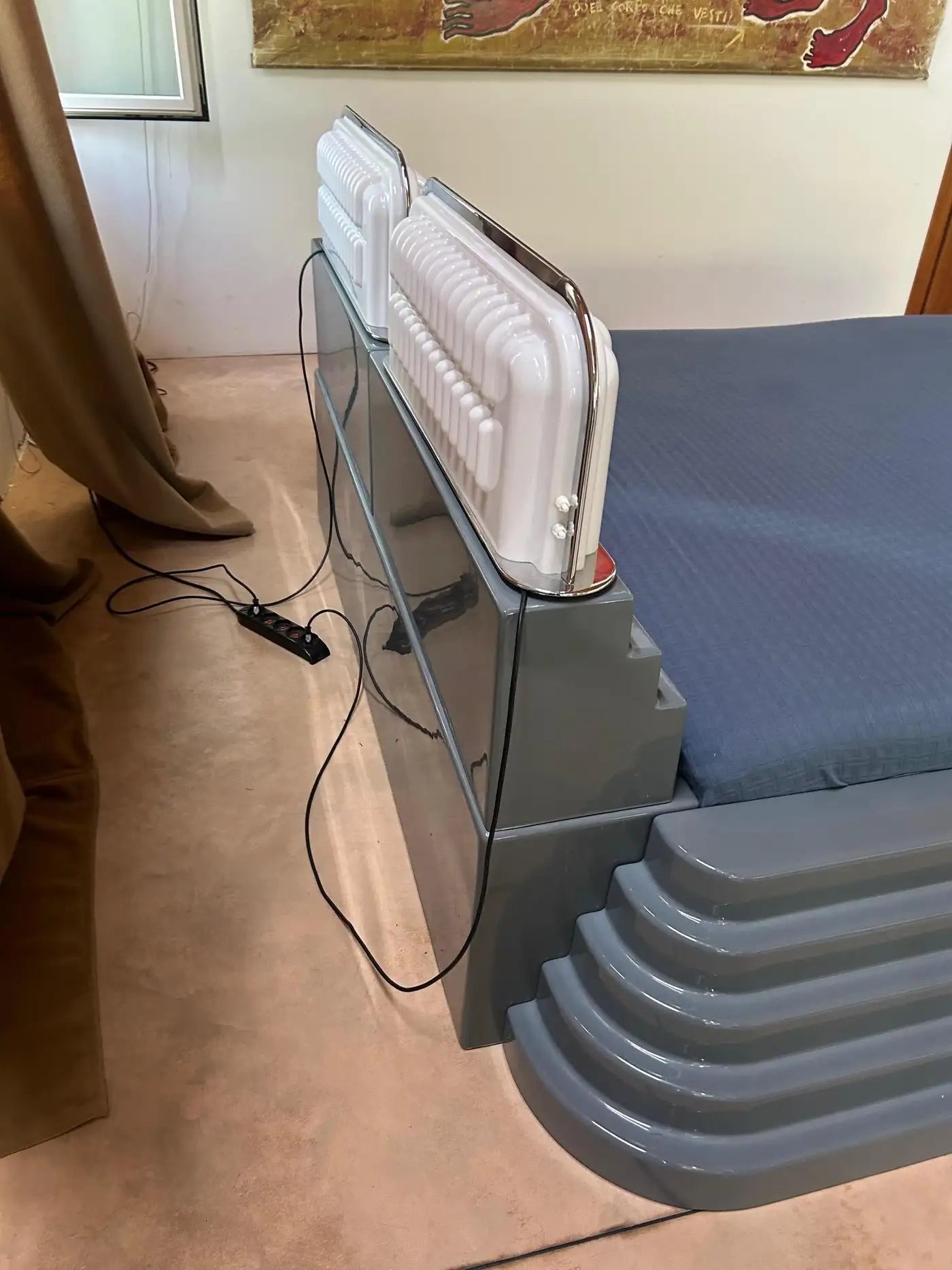 Portable heater on a stand in a room with a painting on the wall.