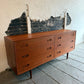 Wooden dresser against a textured wall with peeling paint