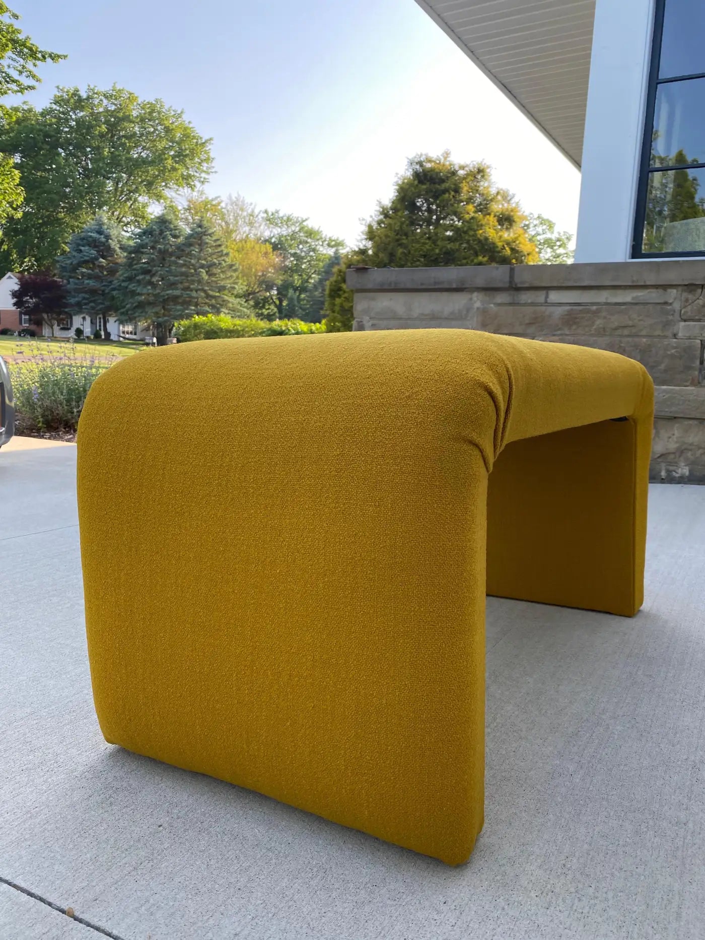 Yellow outdoor bench on a patio with trees and building in the background