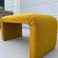 Yellow L-shaped bench on a concrete surface with a white garage door in the background