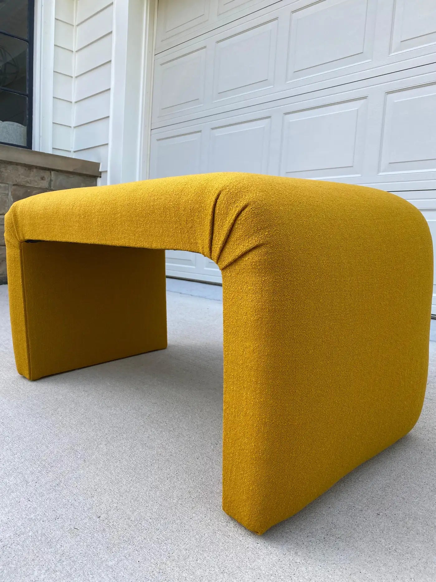 Yellow L-shaped bench on a concrete surface with a white garage door in the background