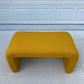 Yellow bench on a light gray floor with a white paneled wall in the background